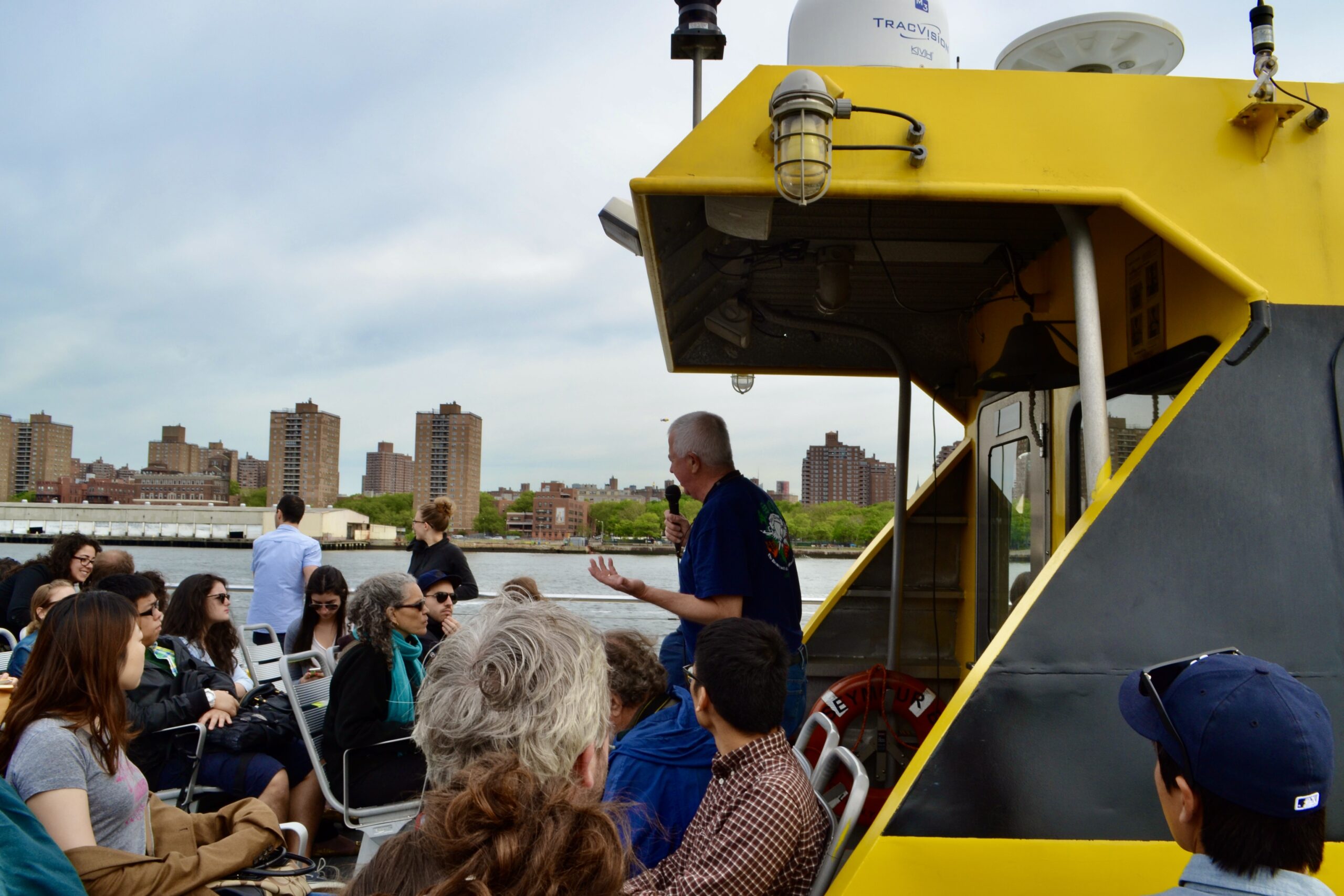 students and faculty on boat, assessing NYC waterfront resilience needs, city in background