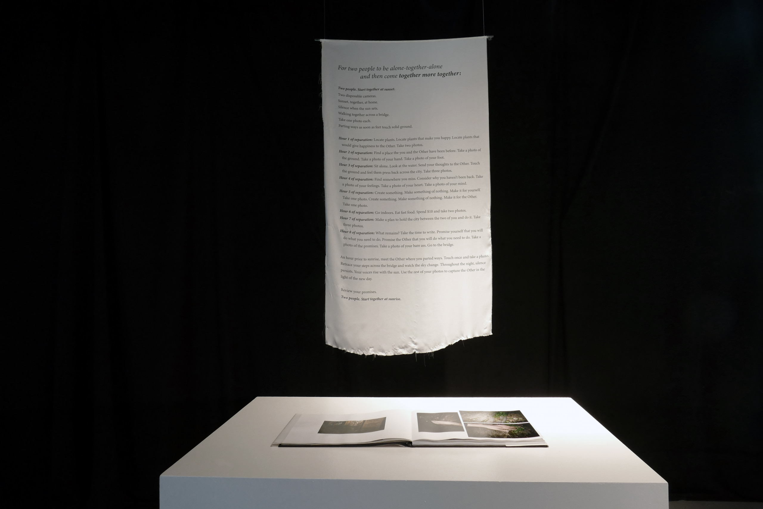 White scroll with text hangs above a white table with open photo book