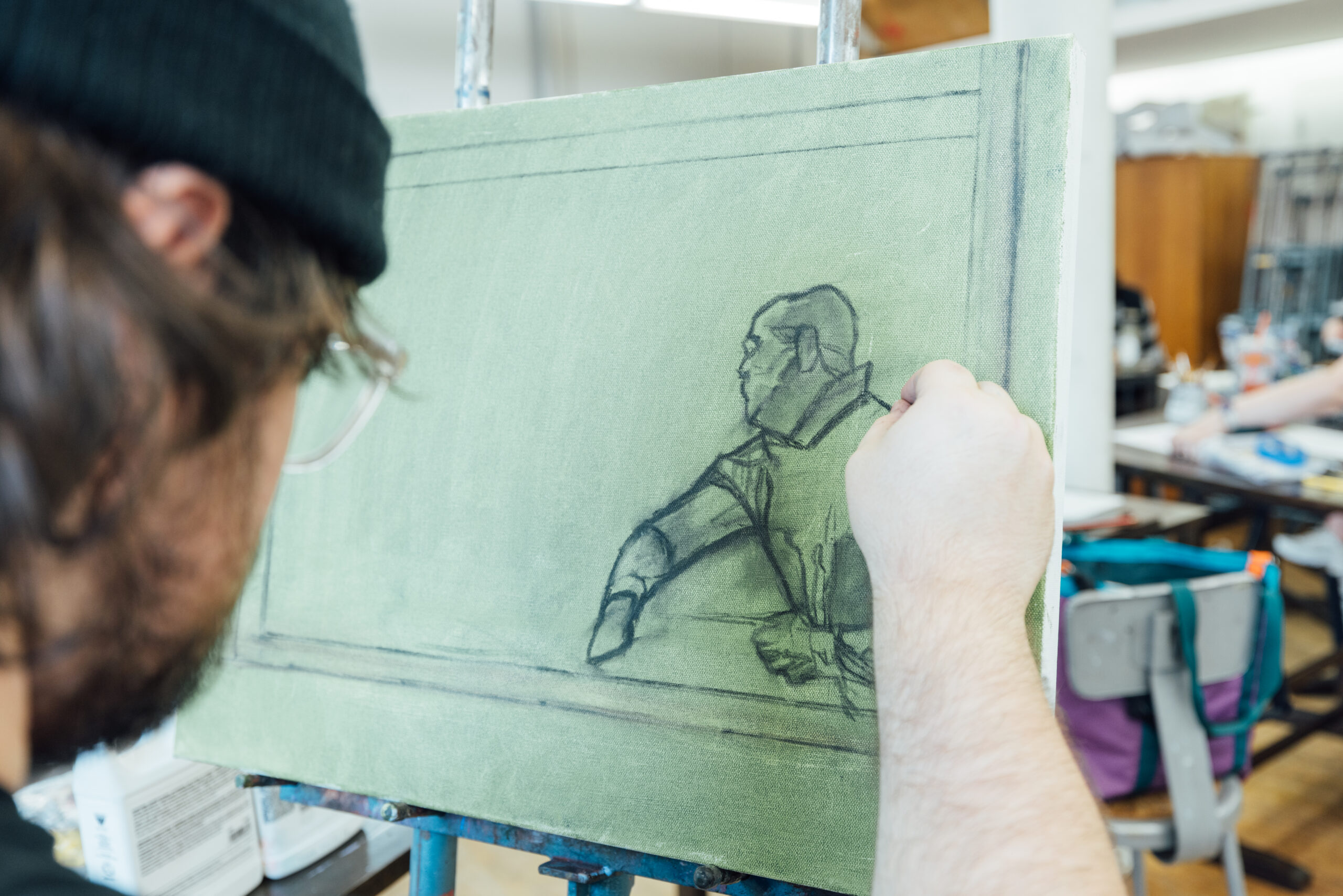 man drawing a figure on a light green canvas