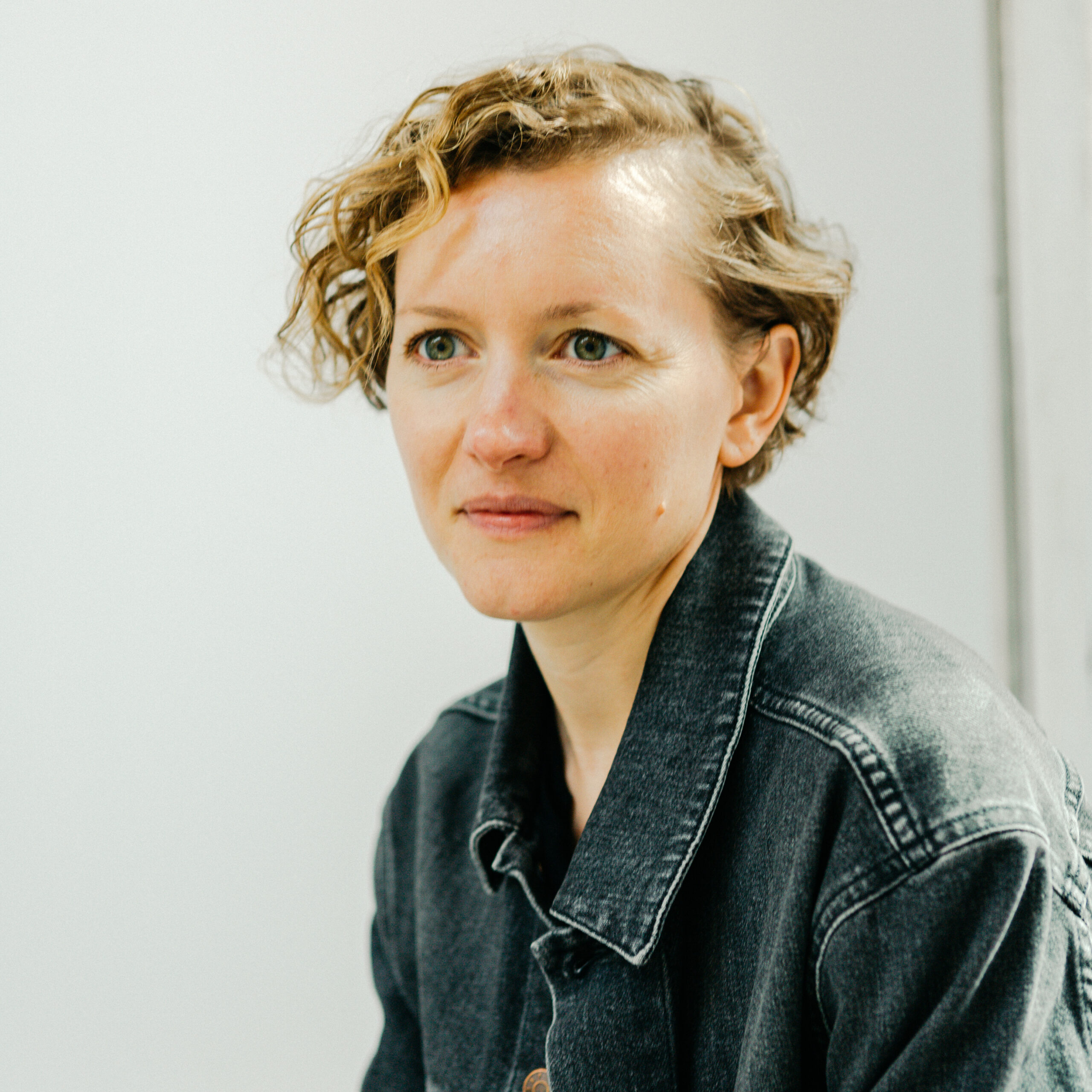 Headshot of white woman with short brown hair and gray denim jacket