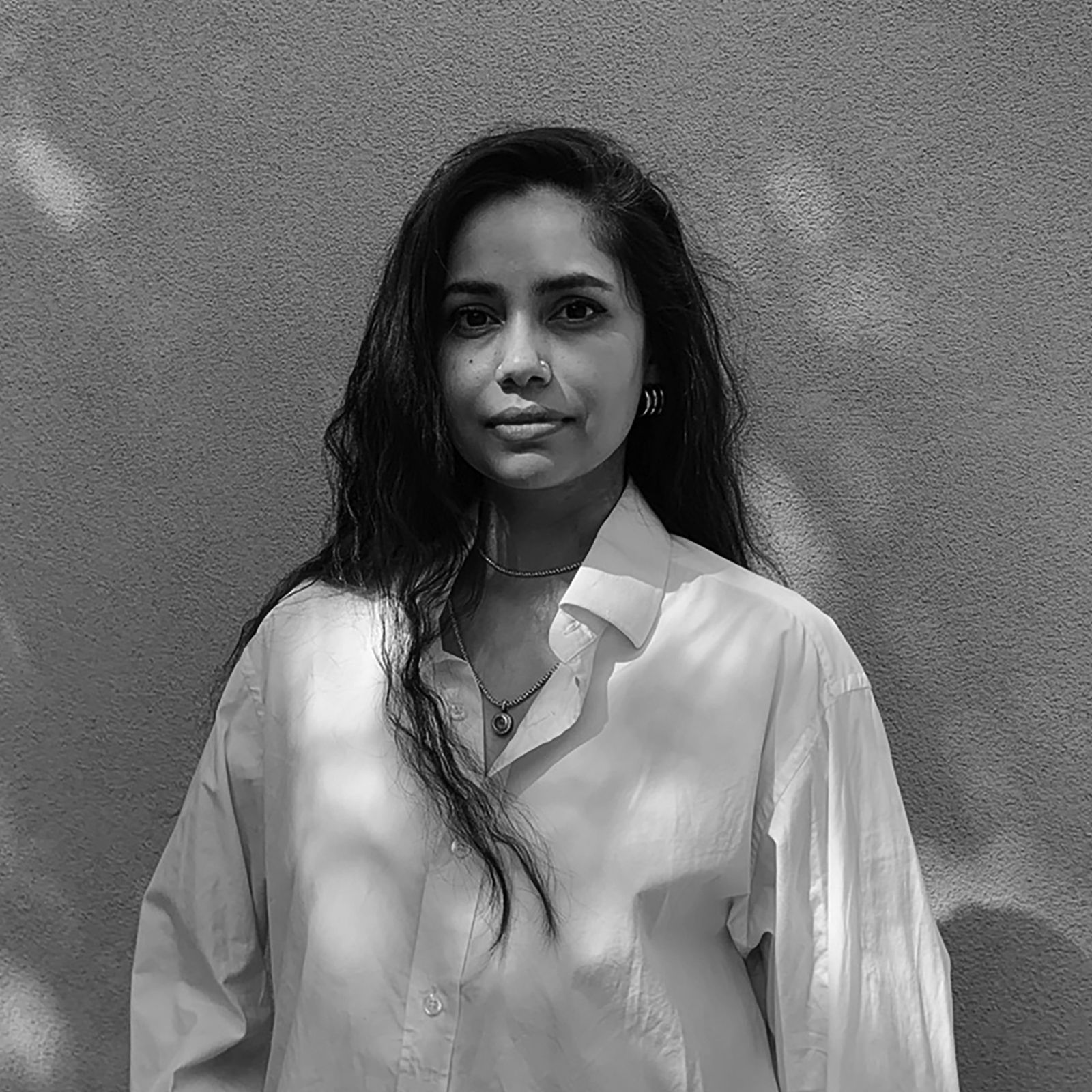 A black-and-white portrait of Swati Piparsania, standing against a plain background, looking directly at the camera with a neutral expression, wearing a light-colored button-up shirt.