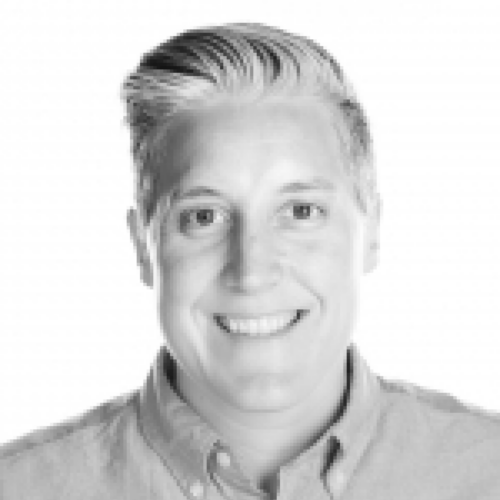 A grayscale professional portrait of Bethany Martin, smiling warmly. Bethany has short, styled hair and is wearing a collared shirt. The background is plain white.