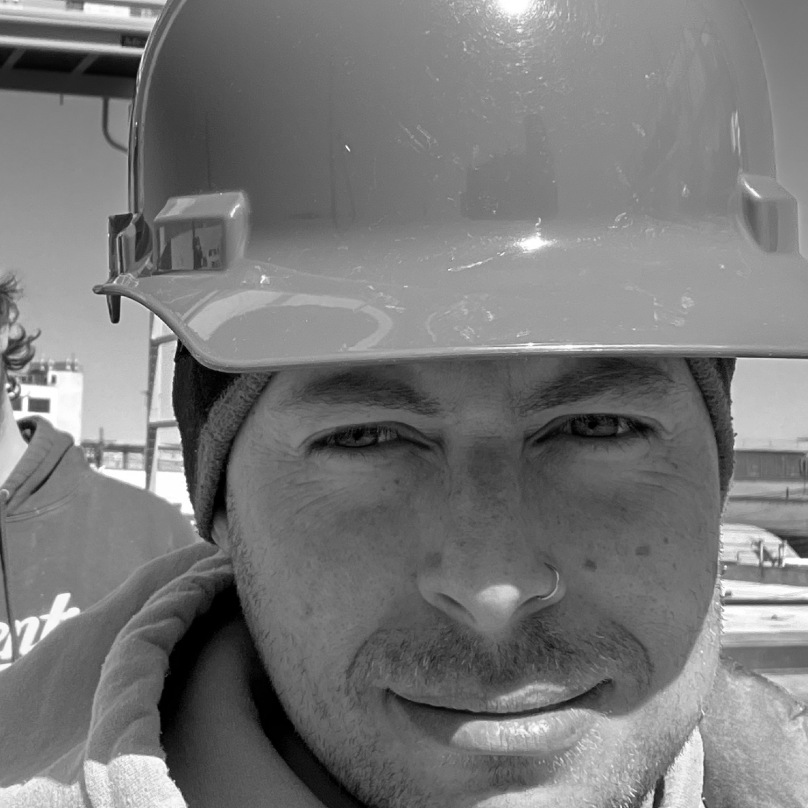 David Kirshoff wearing a hard hat on a construction site, with a close-up of his face, looking into the camera.