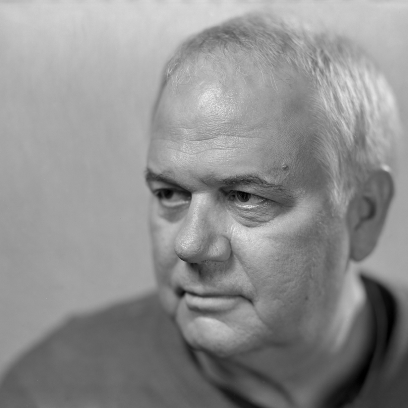 A grayscale portrait of Jeff Tolbert, a man with neatly combed hair, wearing a sweater, gazing thoughtfully to the side.