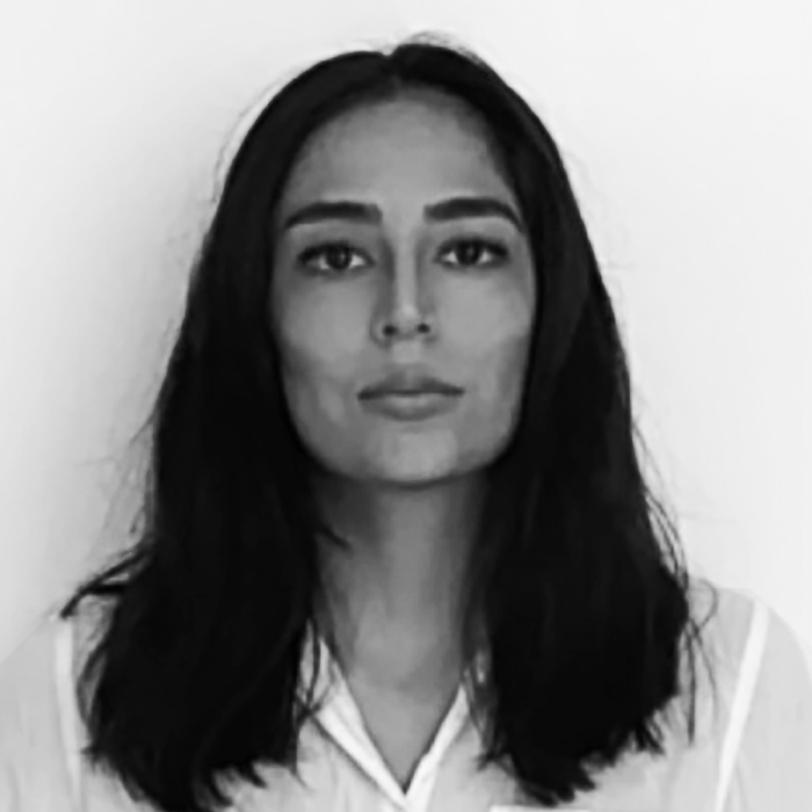 A black and white portrait of a woman with long dark hair, wearing a white blouse, looking directly at the camera with a neutral expression.