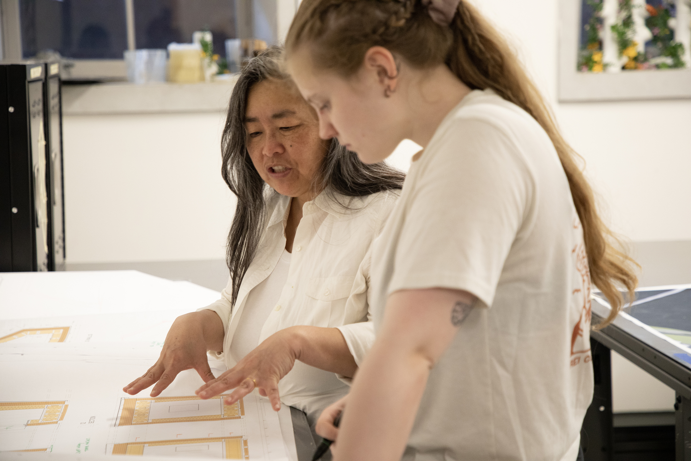 Professor In Cho stands beside a student reviewing architectural drawings