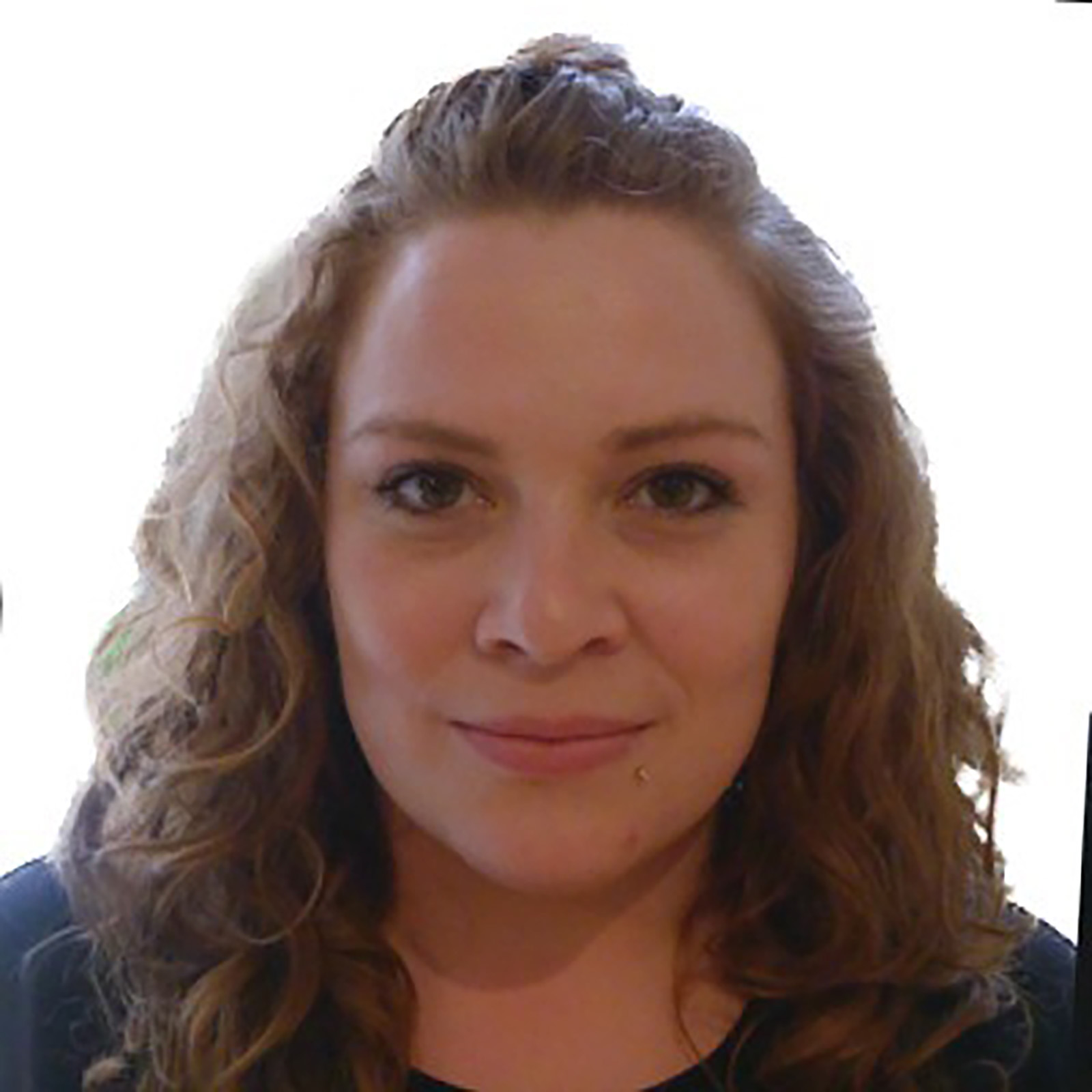 A portrait of a person with curly hair, wearing a dark top, looking directly at the camera with a neutral expression. The background is white.